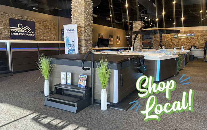 Indoor showroom with hot tubs and pool equipment featuring Shop Local signage and Endless Pools branding