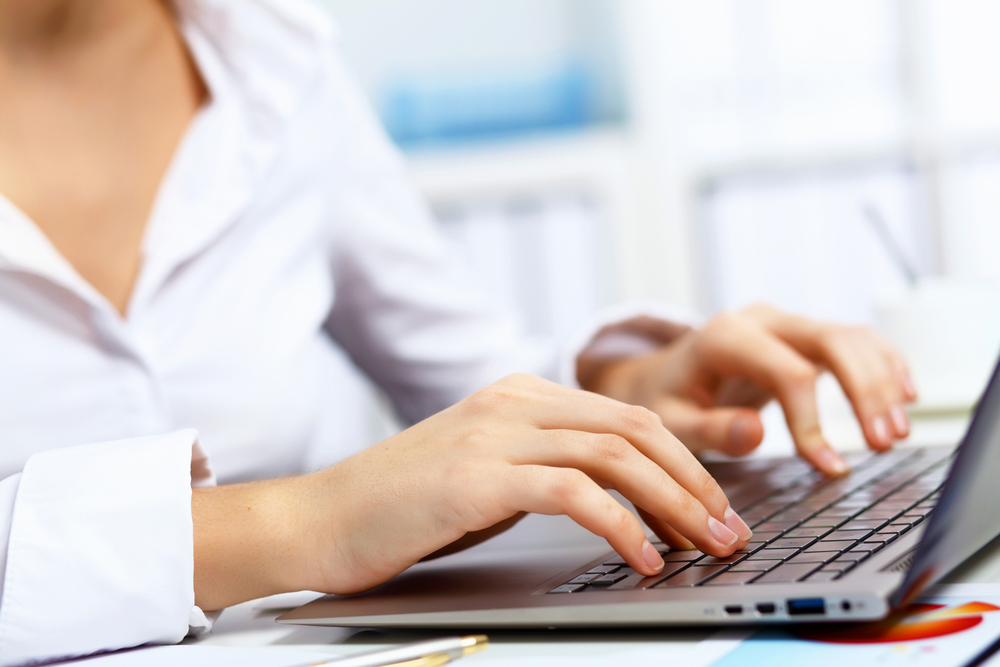 woman's hands typing on a laptop