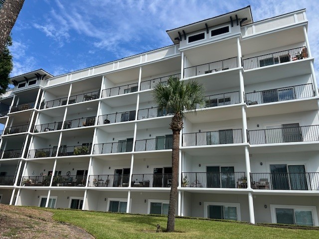 Modern white apartment building with balconies and a palm tree under a blue sky with clouds. Fall Maintenance Checklist for Facility Managers.