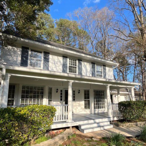 Two-story home with white siding, black shutters, and a covered front porch featured in Ray Lathem Nelson Exteriors employee spotlight by Nelson Exteriors | Siding Contractor & Exteriors Marietta in GA
