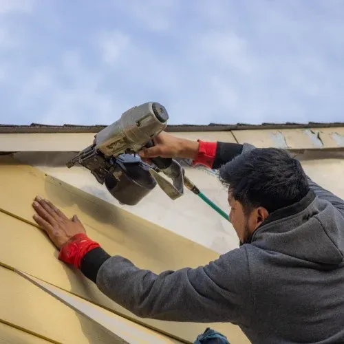 Contractor installing new siding on a home exterior by Nelson Exteriors in Atlanta, GA
