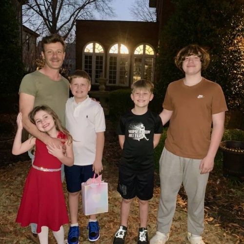Josh Motes with family standing outside a home at dusk by Nelson Exteriors