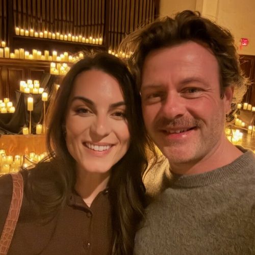 Josh Motes smiling with partner at an indoor event with candlelit background by Nelson Exteriors