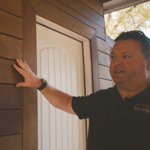 Contractor examining Brazilian hardwood siding finish on home exterior by Nelson Exteriors