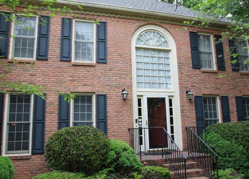 Red brick home with old white windows and a single entry door.