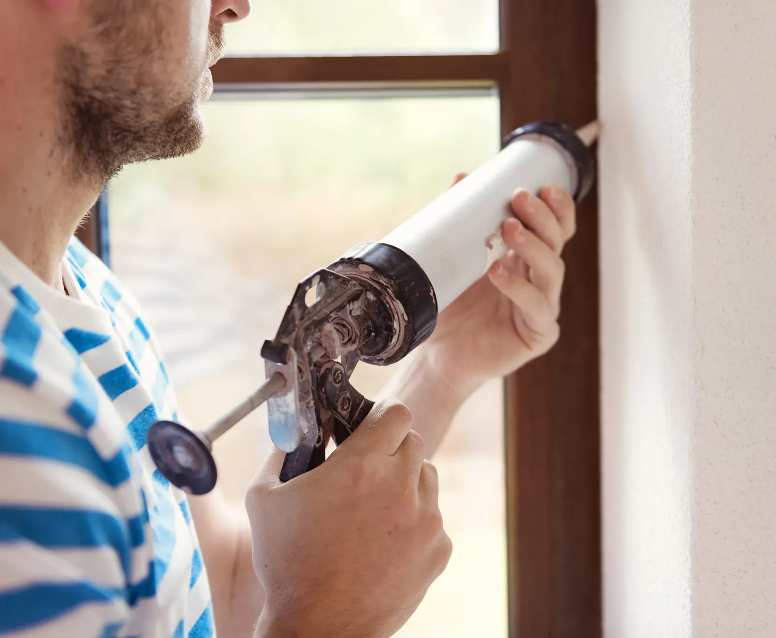 Window installation contractor applying caulk around a window frame