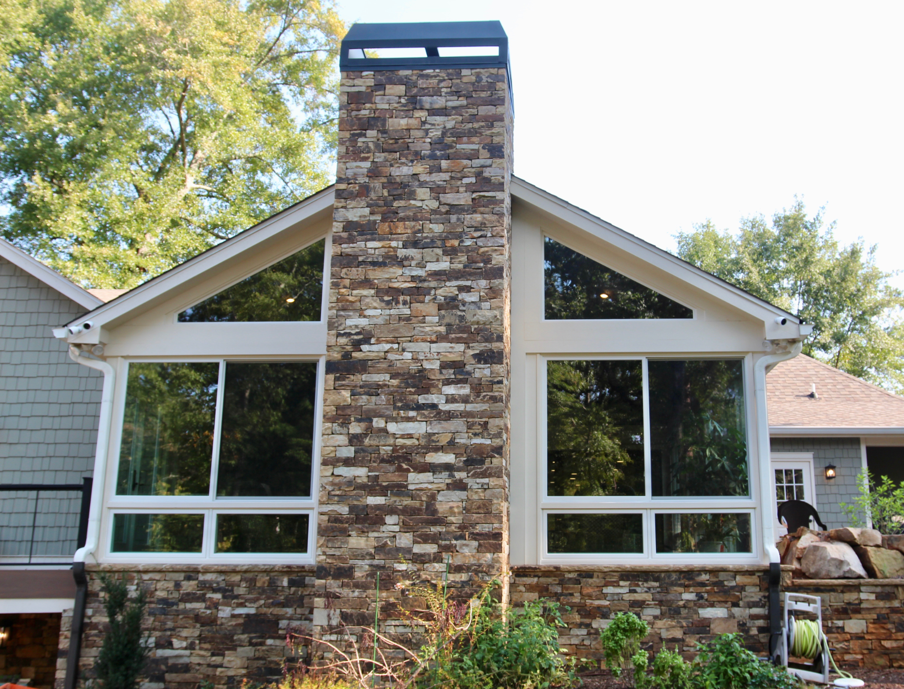 White fiberglass slider windows with a stone chimney in the center