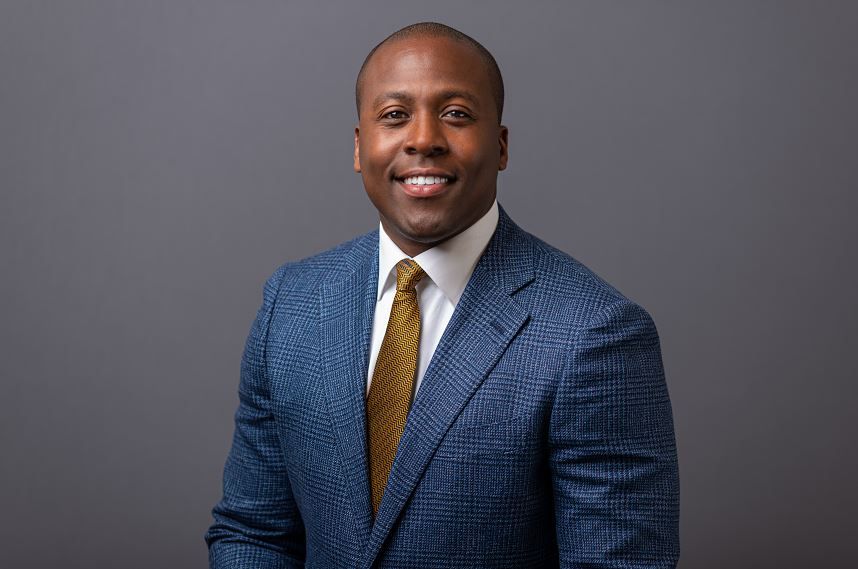 Dr. Elvis Francois poses in front of a gray backdrop.