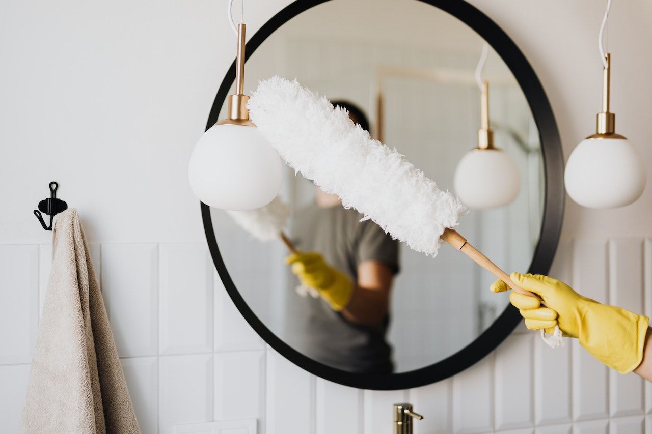 dusting bathroom lights in front of a bathroom mirror