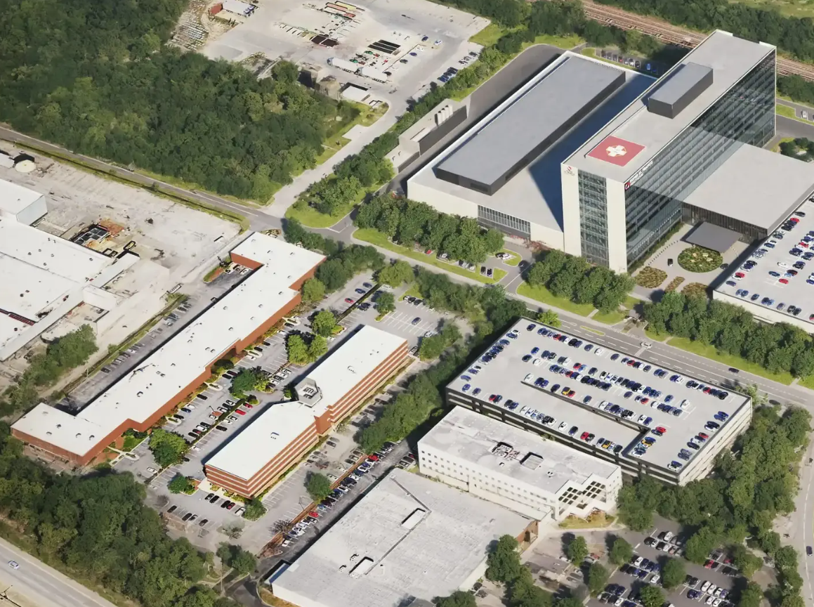 Aerial view of a business park with multiple office buildings and large parking lots surrounded by greenery.