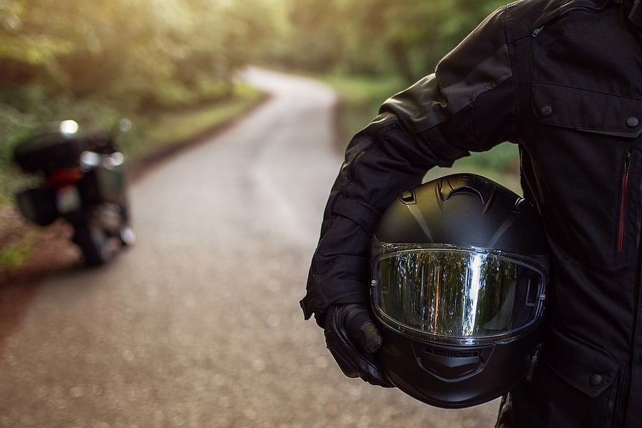 A person carrying a helmet walking down the road