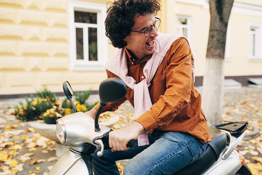 A person driving a moped with a smile