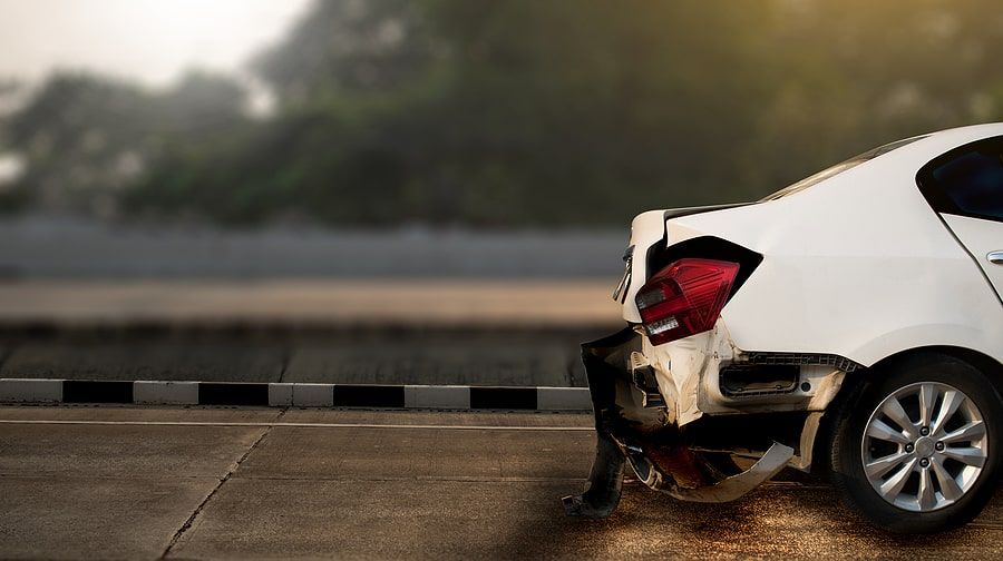 A white car that is wrecked on the road