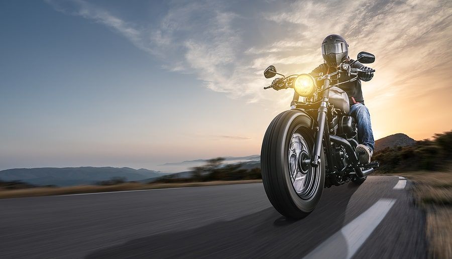 Close up view of someone riding a motorcycle in the sunet