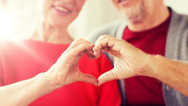 A couple wearing red holds their hands together in a heart shape