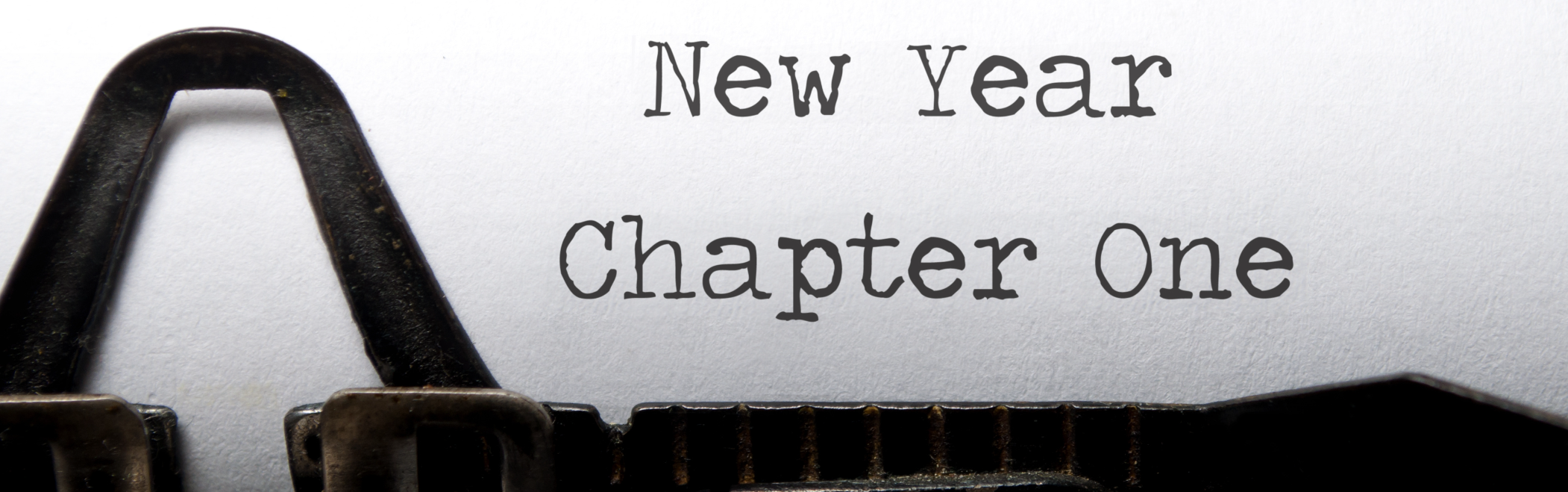 Closeup of a white piece of paper in a typewriter saying 'new year chapter one'