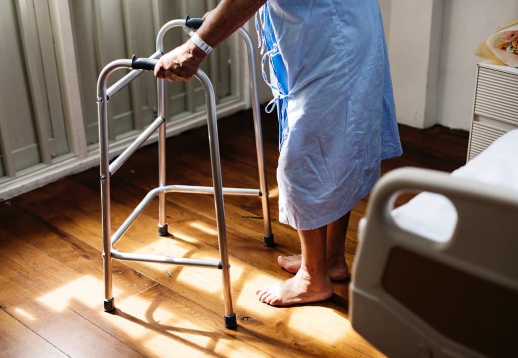 an elderly person standing up and holding a walker
