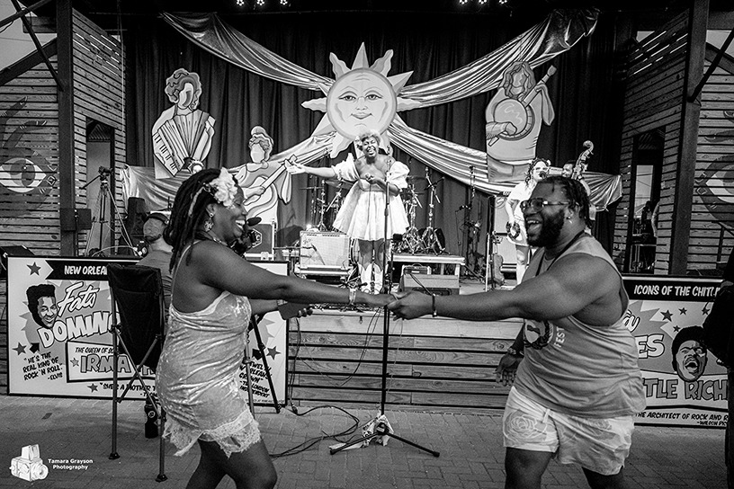 Black and white photo of a happy couple dancing in front of a live band performing on stage with sun and music decor.