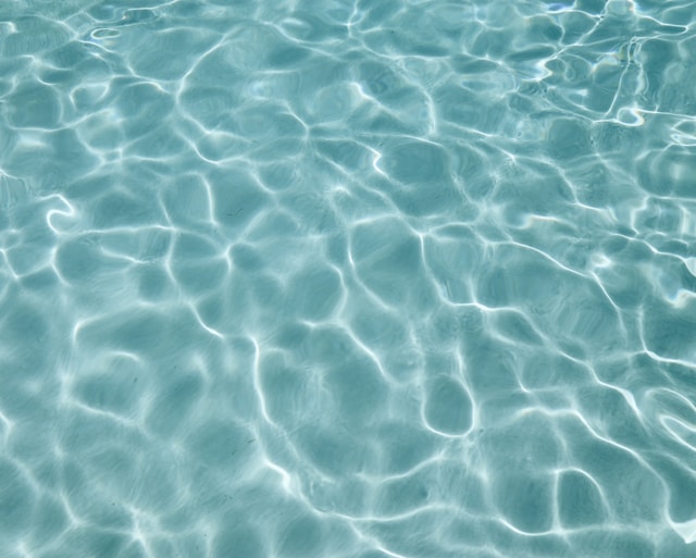 Clear blue water surface with sunlight reflections creating ripples and shimmering patterns.