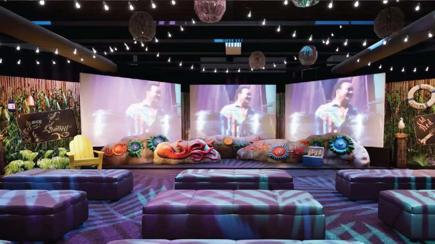 Indoor lounge with colorful cushions, purple seating, hanging lights, and projected video screens on walls
