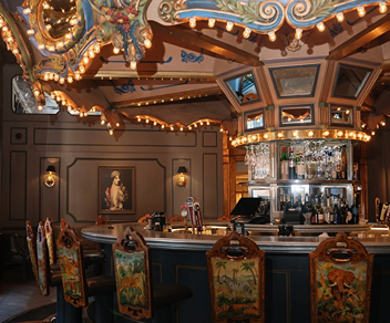 Vintage carousel-themed bar with ornately decorated chairs and warm ambient lighting