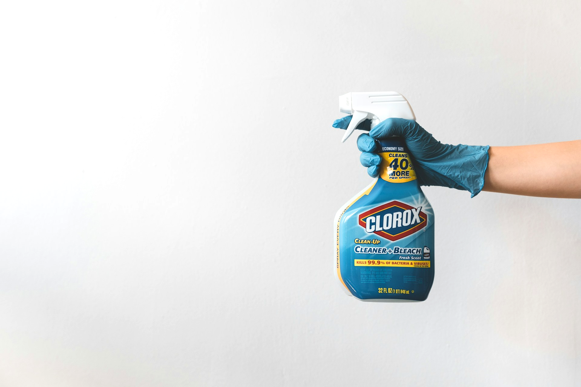 Gloved hand holding a bottle of Clorox Cleaner plus Bleach