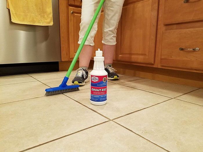 a person cleaning a floor with grout cleaner