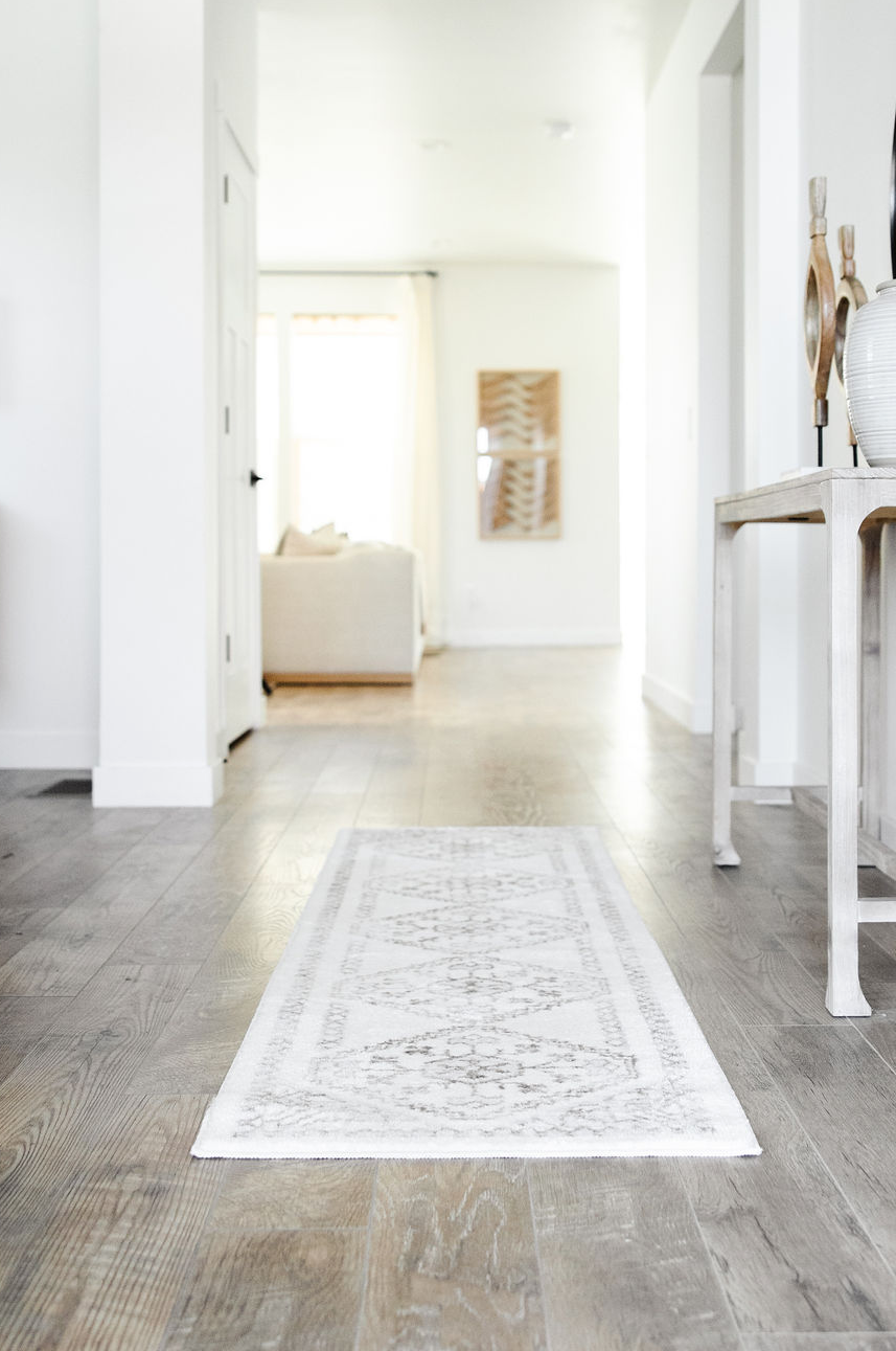 how to get rid of slippery hardwood floors is by installing area rugs and door mats like this white rug runner by a table