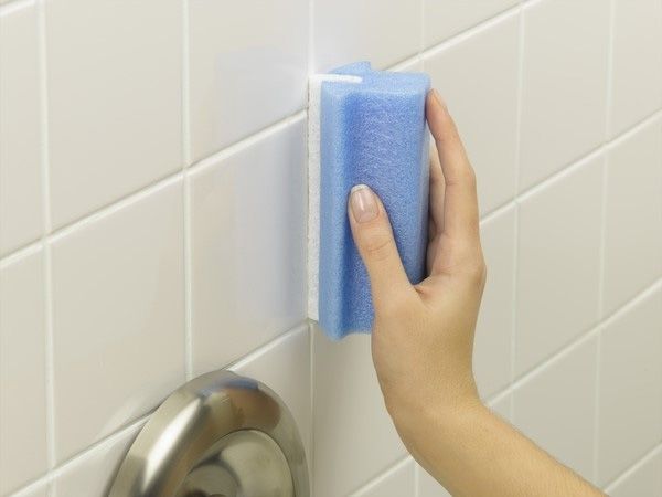 a person cleaning bathroom tiles with a sponge