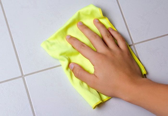 a person cleaning tiles with a rag