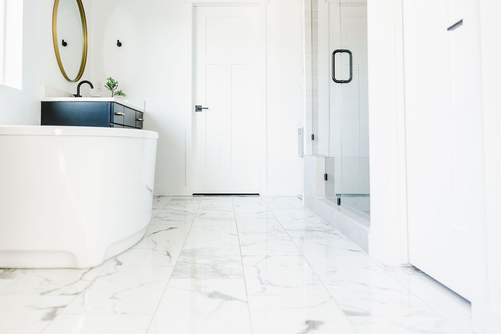 Very white bathroom, with a bathtub on the left, with slippery marble tiles