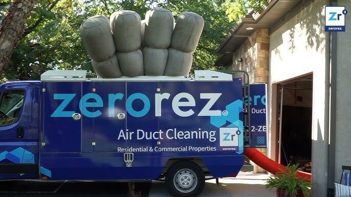 Blue Zerorez Negative Air Duct Cleaning truck inflated, with a red hose coming out and going into the garage of a house