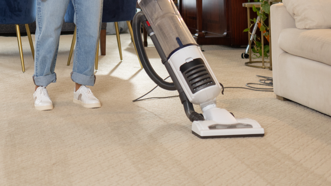 person in white shoes and jeans pushing around a noisy loud white vacuum cleaner