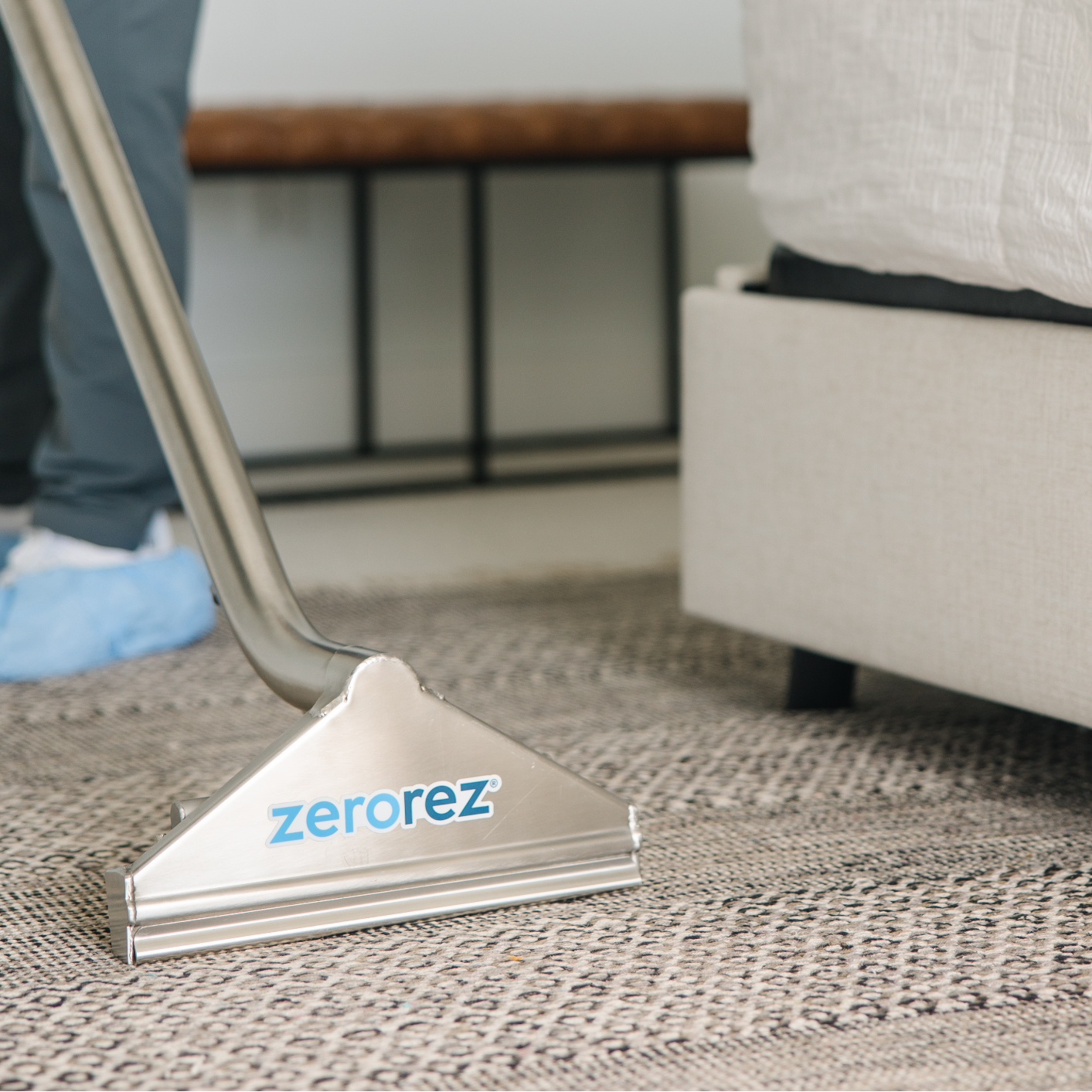 Close up of the front of the Zerorez Zr Wand cleaning an area rug on top of a carpet to help prevent it from moving around