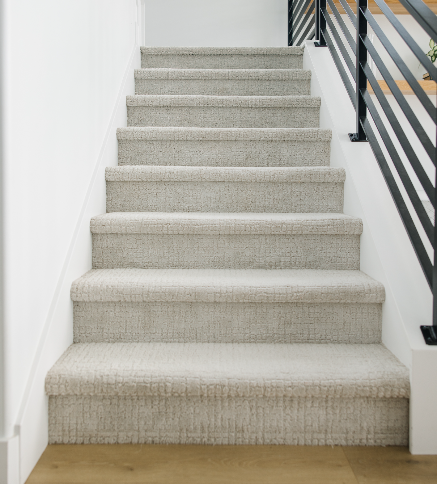 carpeted stairs with a black metal railing on the right side in need of carpet cleaning edges on stair