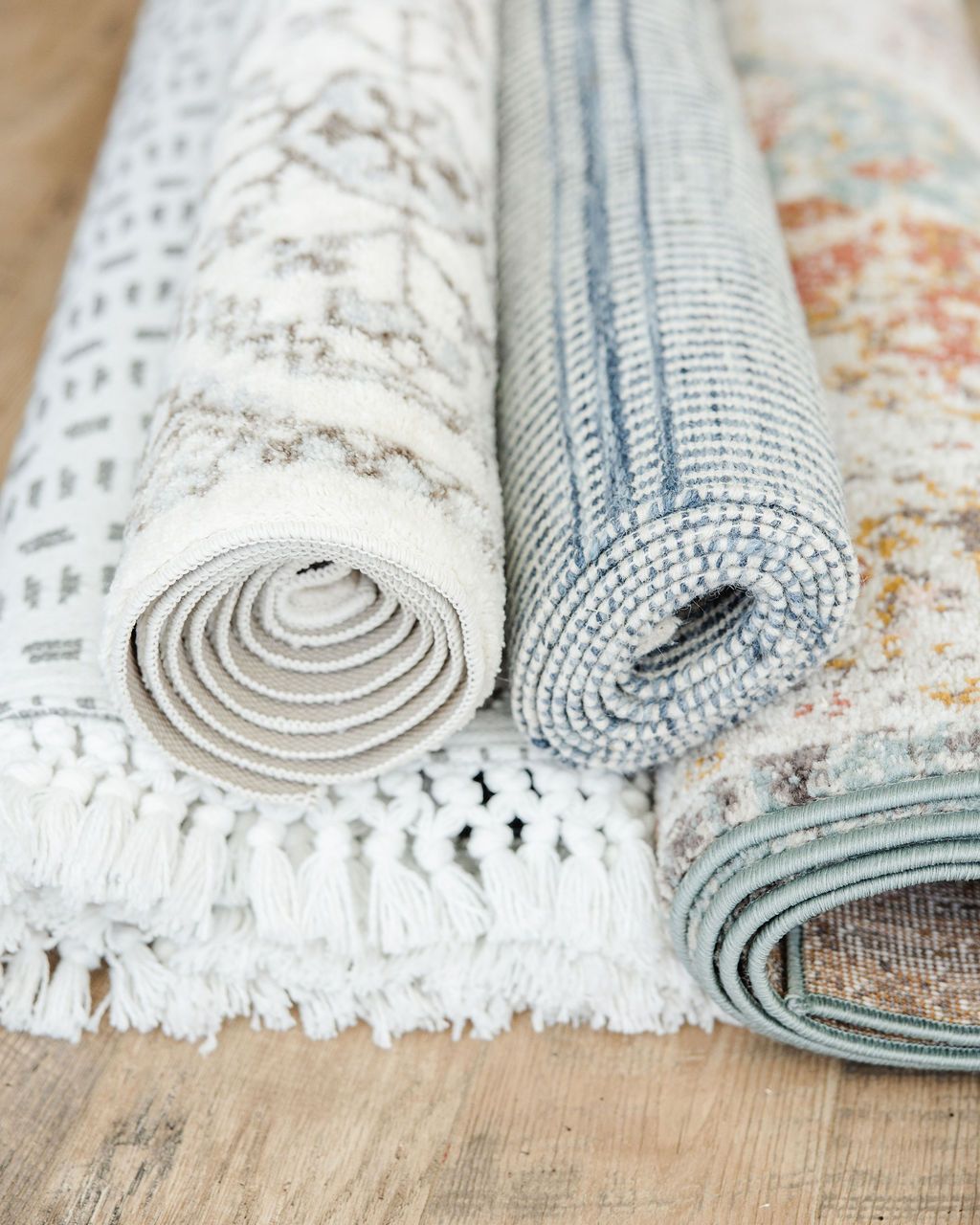 a pile of different rugs in colors on wood floors