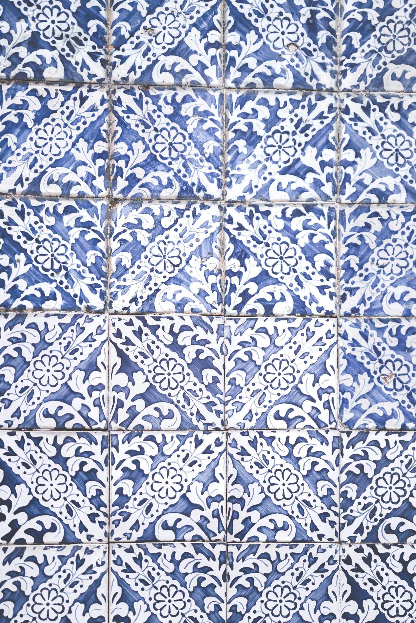 patterned blue and white tiles with cracking grout between them