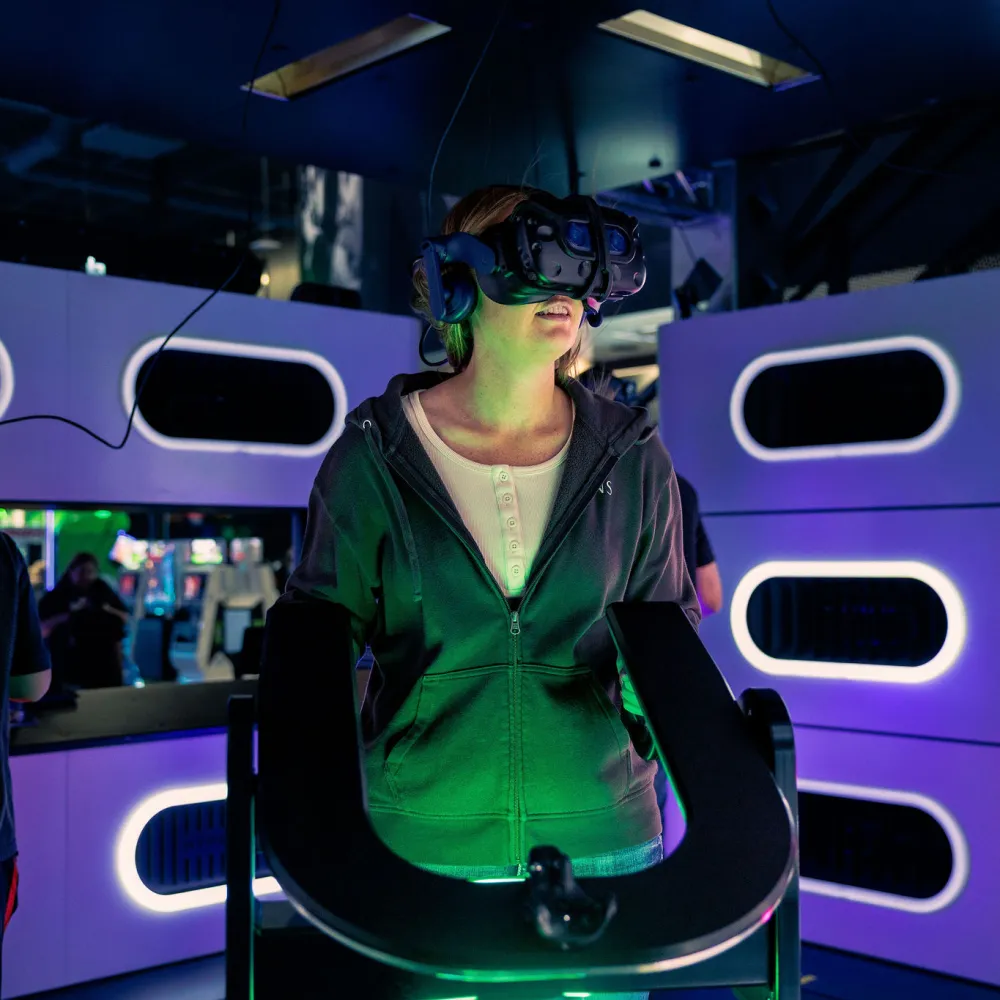 People immersed in virtual reality gaming in a neon-lit VR arcade wearing headsets and headphones