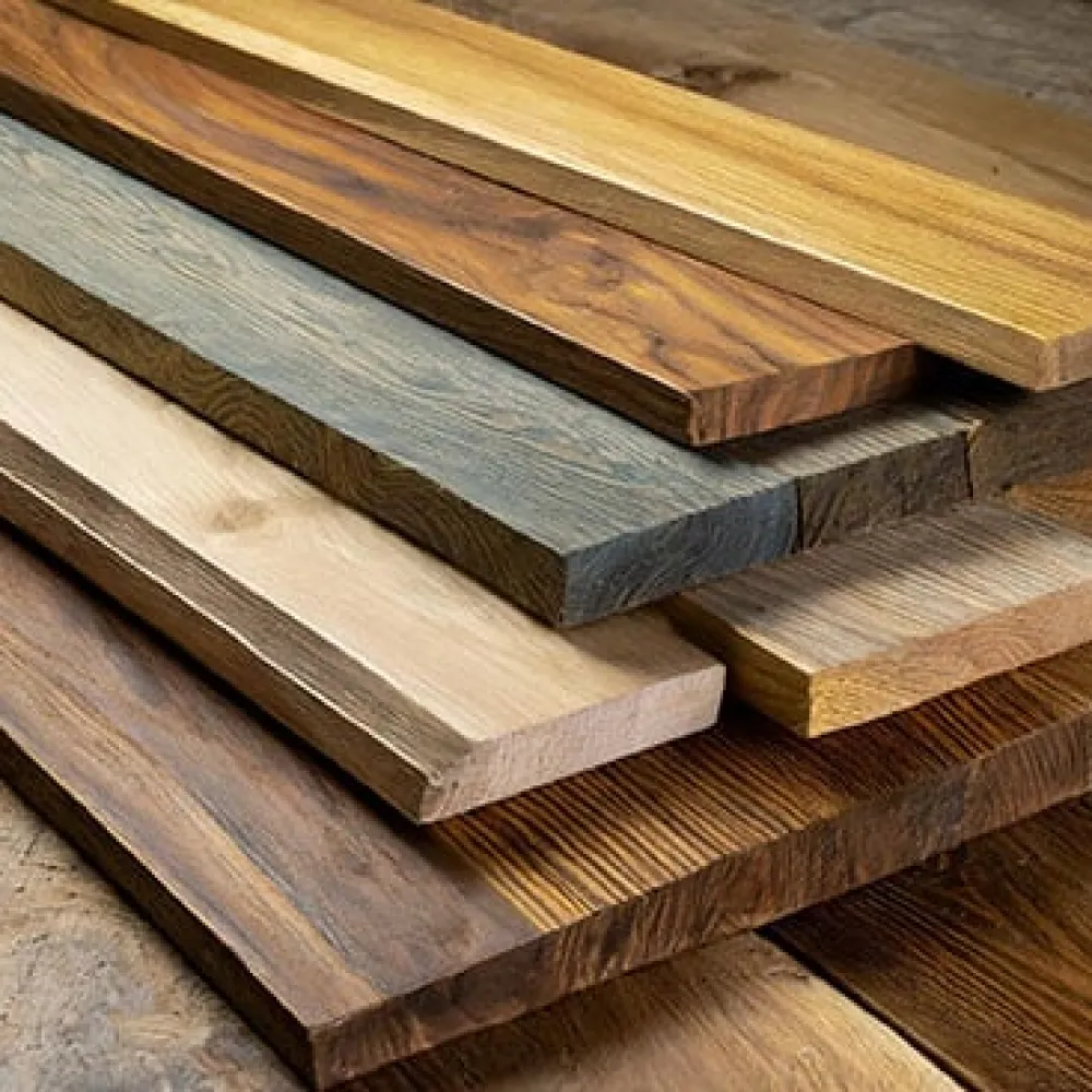 Stack of various wooden planks showcasing different colors, grains, and finishes on a wooden surface.