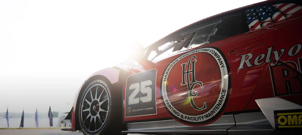 Close-up of race car number 25 with sponsor logos and sun glare at a racing event.