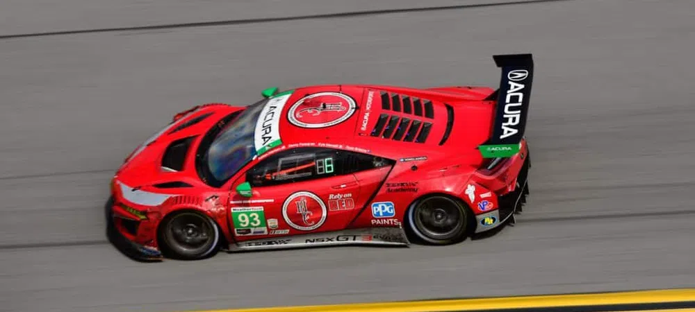 Red Acura NSX GT3 race car number 93 speeding on track with black rear wing and sponsor logos