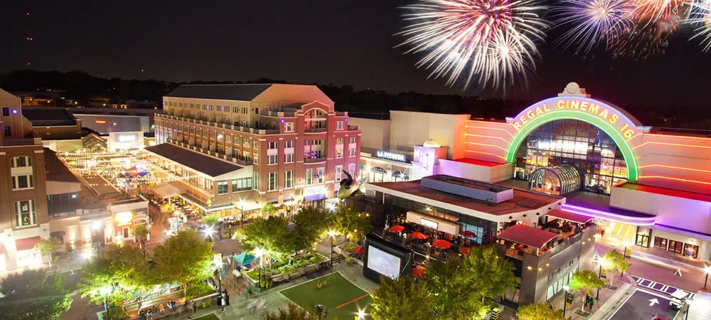 Night scene of the vibrant shopping plaza Atlantic Station with crowds, Regal Cinemas lit up and fireworks in the sky