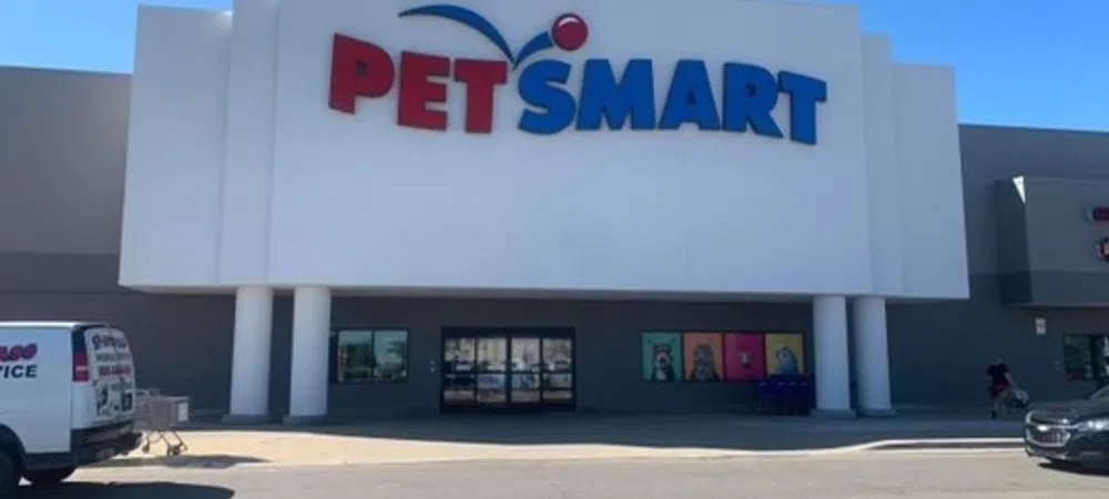 PetSmart storefront with large red and blue logo on white facade under clear blue sky.