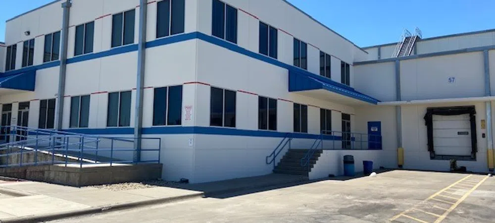 Modern industrial warehouse exterior with loading dock and accessibility ramp under clear blue sky.
