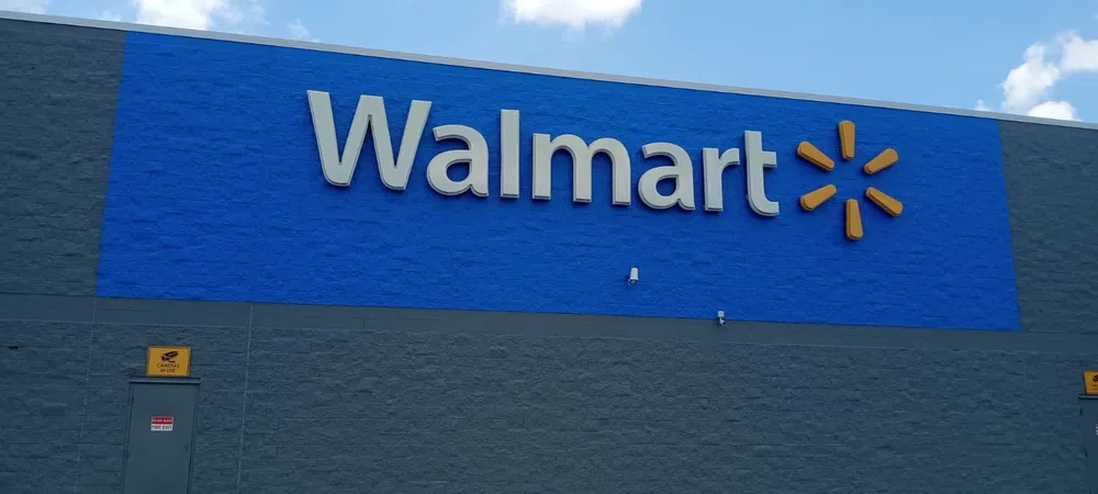Exterior of a Walmart store with large blue signage and gray walls under a partly cloudy sky.