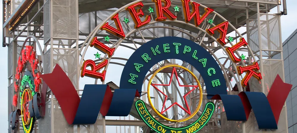Colorful neon sign archway reading Riverwalk Marketplace Festival on the Mississippi with star and decorative elements.