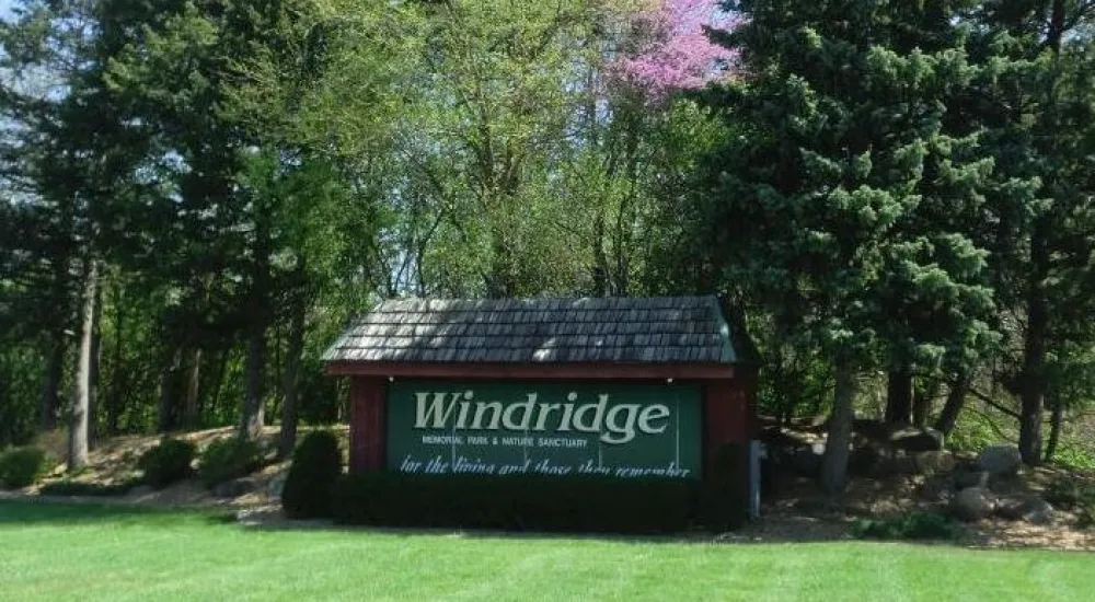 a small building with a sign in front of trees