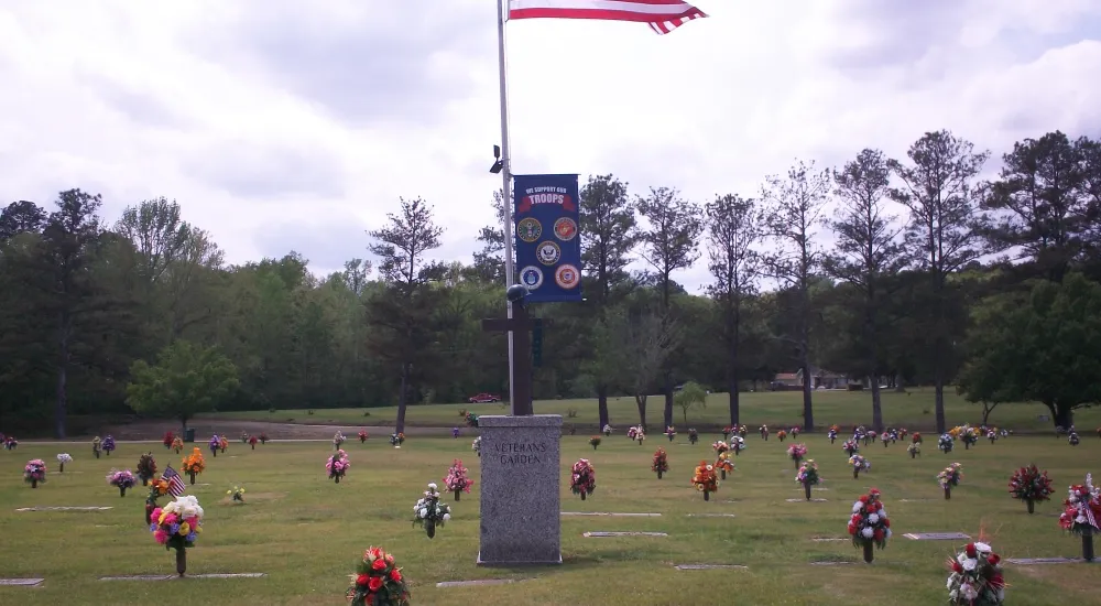 a flagpole with a flag on it in a park with people