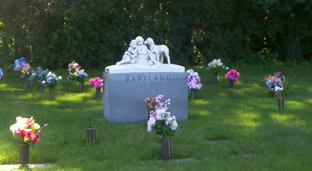 a grave stone with flowers and a statue of a person on a horse