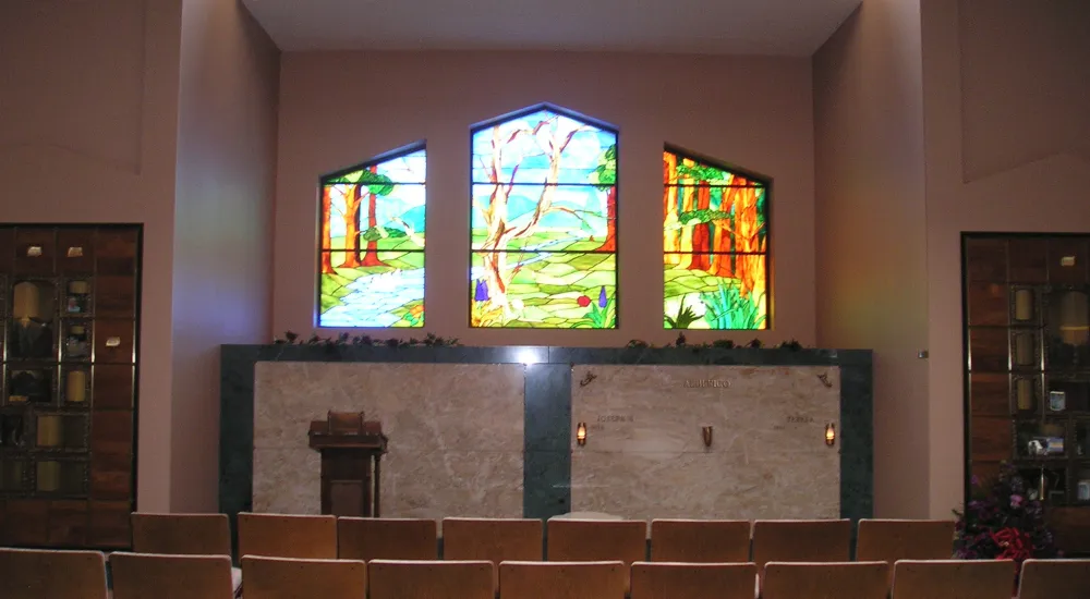 a room with chairs and a stage with stained glass windows